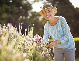 Smiling woman with dental implants in Castle Rock picking flowers
