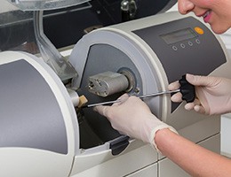 A dental professional inserting a block of porcelain into a milling unit to craft a CEREC crown 