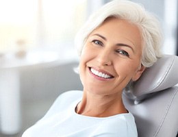 Older woman smiling in the dentist’s chair after receiving cosmetic dentist in Castle Rock