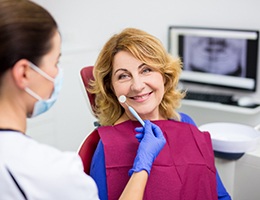 Woman in dentist’s chair smiling with dentures