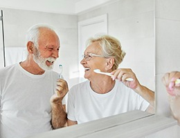 Couple smiling and brushing their teeth