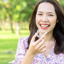A young woman outside and preparing to insert her top Invisalign aligner