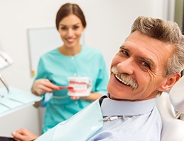 An older gentleman smiling after receiving implant-retained dentures in Castle Rock