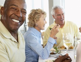 Older man sitting with friends at a dinner table 