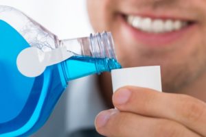 a man pouring mouthwash into a cup so he can rinse before seeing his dentist 