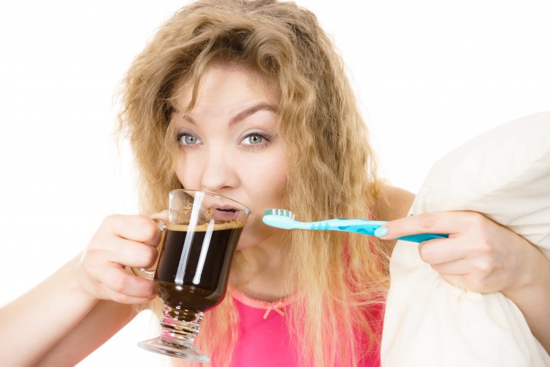 woman drinking coffee and holding a toothbrush