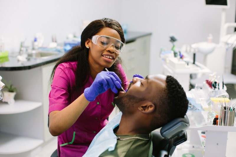 a dental hygienist performing a regular checkup and cleaning on a male patient